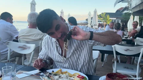 Man Holding Cooked Fish Head at Beach Restaurant 库存影片 339884462