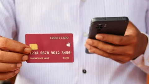 Man holding a credit card while using a smartphone Stock Footage 337694768