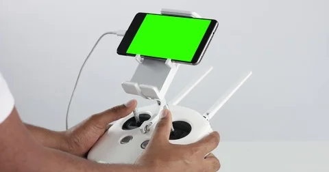 Man holding a cuadrocopter control remote and using a smartphone with green Video stock 76995574