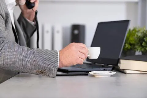 Man holding a cup of coffee while talking on the phone Stock Photos