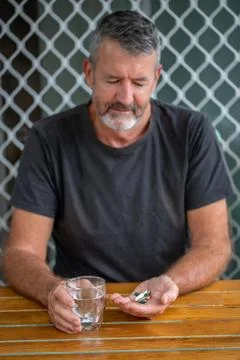 Man holding different tablets and a glass of water Stock Photos