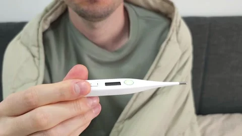Man holding a digital thermometer while wrapped in a blanket. Stock Footage 284045840