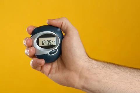 Man holding digital timer on yellow background, closeup Foto stock