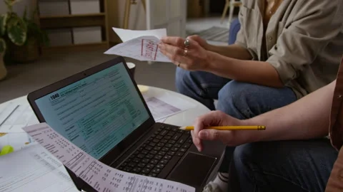 Man Holding Documents in Hand and using Laptop Filling in Tax Forms with Wife Stock Footage 327685631