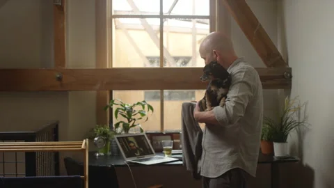 Man holding a dog while folding laundry and having a video chat Video stock 133295510