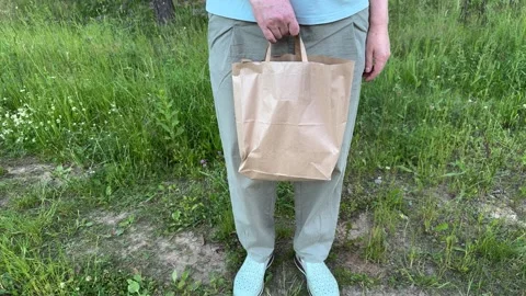 Man holding eco-friendly craft bag outdoors in forest Видео 338035835