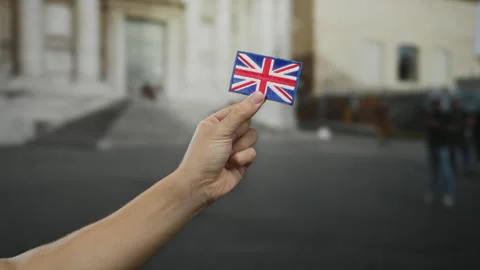 Man holding an embroidered union jack flag patch in an outdoor city street .. Stock Footage 314291364