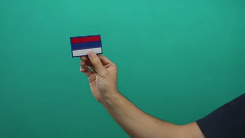 Man holding embroidery patch of russian flag against a vibrant green wall b.. Stock Footage 315147414