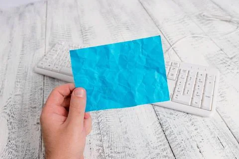 Man holding an empty rectangle shaped paper note, white keyboard in the ba... Stock Photos