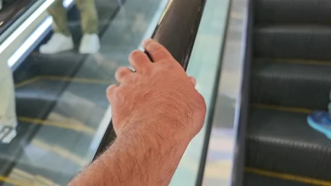 Man holding escalator handrail while going up Vidéo 310300318