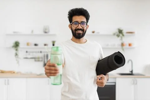Man Holding Exercise Mat and Water Bottle at Home Stock Photos
