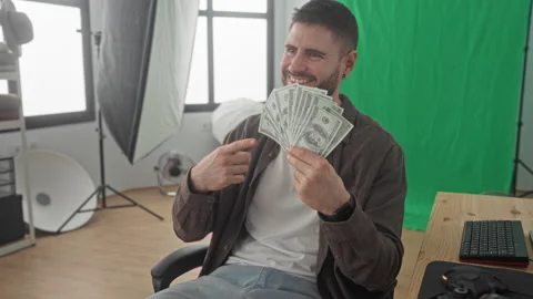 Man holding a fan of dollars and pointing finger at the cash in a studio wi.. Stock Footage 337363103