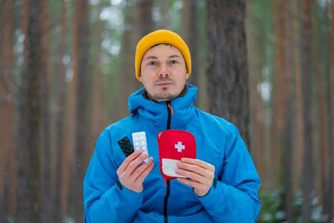 Man holding first aid kit and medication during winter hike Stock Photos