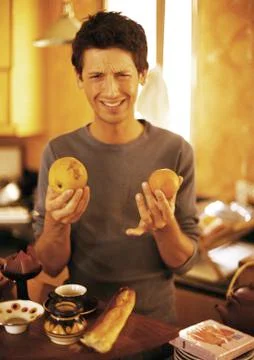 Man holding up fruit and making face, portrait Stock Photos