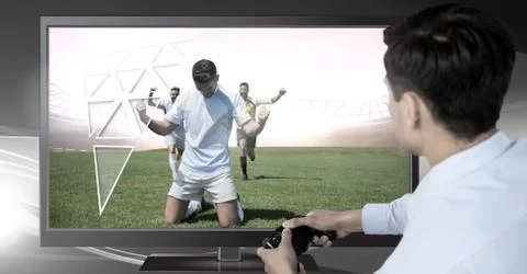 Man holding gaming controller  with soccer players celebrating on television Stock Photos
