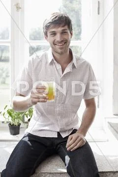 A man holding a glass of juice and smiling Stock Photos