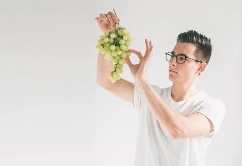 Man holding grape, close up. concept. isolated on white. Nerd is wearing glasses Stock Photos