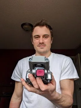 A Man Holding A Gray Drone Inside Showing Technology Hobby &amp; Aerial Camera Stock Photos
