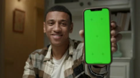 Man holding green screen on mobile phone. African American man shows smartphone Stock Footage 220768560