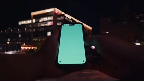 Man Holding Green Screen Smartphone At Night - City Lights Background Stock Footage 309475238