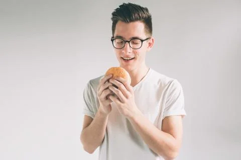 Man holding hamburger. student eats fast food. not helpful food. very hungry man 写真素材