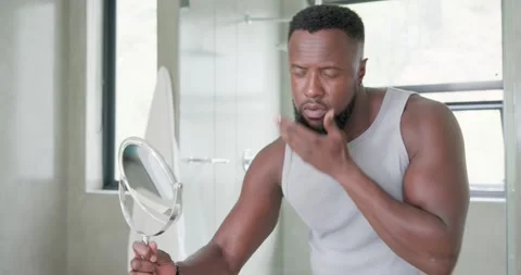 Man holding hand mirror bringing it closer, inspecting beard contours, applying Stock-Footage 337625313