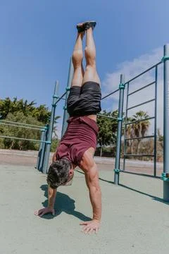 A man is holding an handstand pose during a workout session outdoors Stock Photos