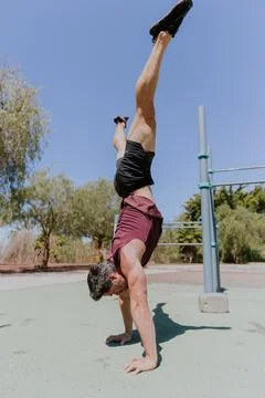 A man is holding an handstand pose with open legs during a workout session .. Stock Photos