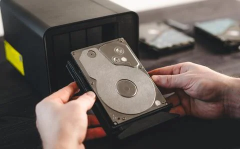 Man Holding A Hard Disk Drive From Bay Of Home Nas Server Storage System Stock Photos