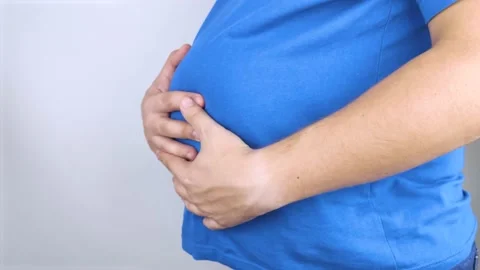 The man is holding onto his swollen belly. Bloating, flatulence, gas, malfunctio Stock Footage 141017796