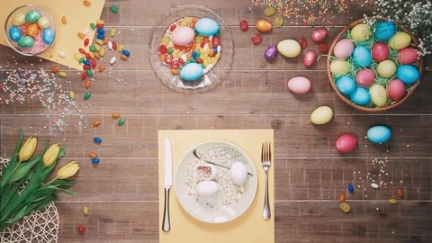 Man holding knife and fork before plate with easter eggs on table decorated with Stock Footage 73943612