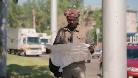 Man holding large hand drawn map on busy street with cars and buildings under Vídeos de archivo 345128405