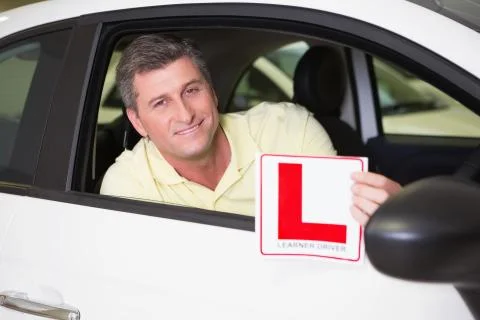 Man holding a learner driver sign sitting behind the wheel Stock Photos