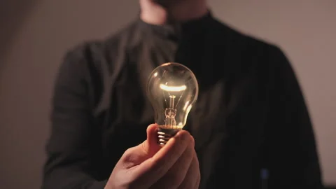 Man holding a light bulb and it turns on, concept of idea Stock Footage 240690103