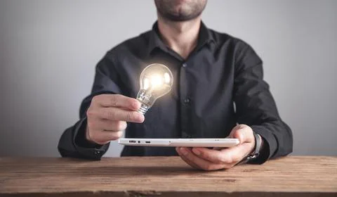 Man holding light bulb with a tablet. Inspiration, Technology, Creativity, Bu Stock Photos