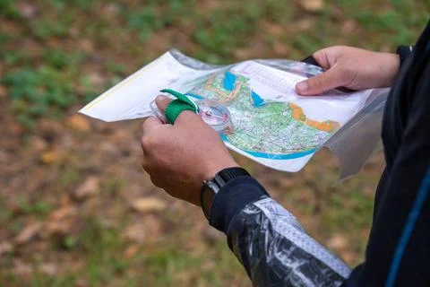 Man holding a map and the compass during orienteering competitions. Stock Photos