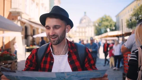 Man holding a map looking at her speak on phone looking around smile happy young Video stock 92072912
