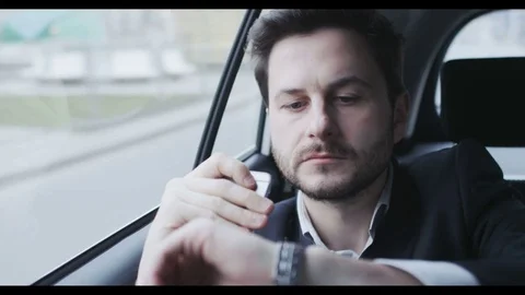 Man Holding a Mobile and Checking Hour on his Watch Stock Footage 74498197