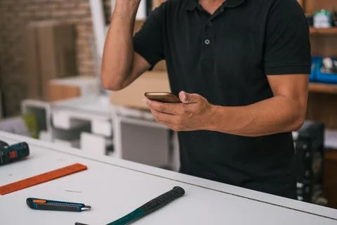 Man holding a mobile in a construction workshop Stock Photos