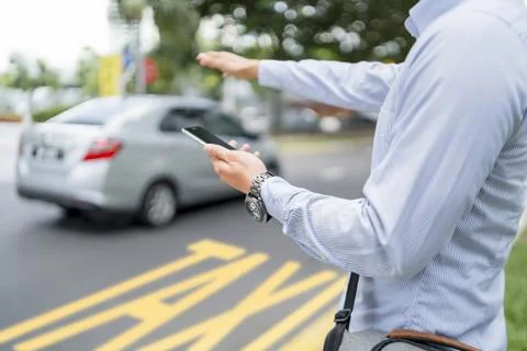 Man holding a mobile phone while hailing for a ride Stock Photos