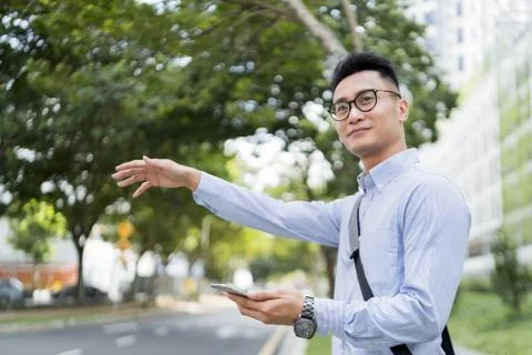 Man holding a mobile phone while hailing for a ride Stock Photos