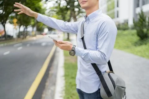 Man holding a mobile phone while hailing for a ride Stock Photos