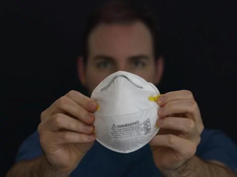 Man Holding Up an N95 Respirator Dust Mask Stock Photos