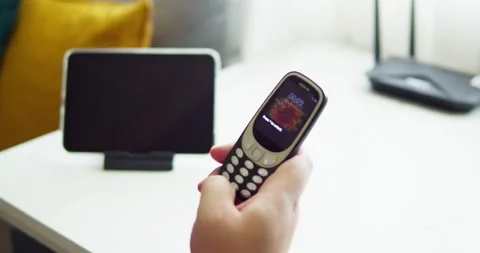 Man holding old mobile NOKIA 3310 try to use and touch button and check Video stock 197595985