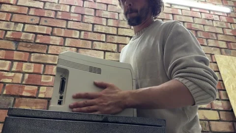 Man holding old printer near wall, handling equipment and preparing for Stock Footage 337110533