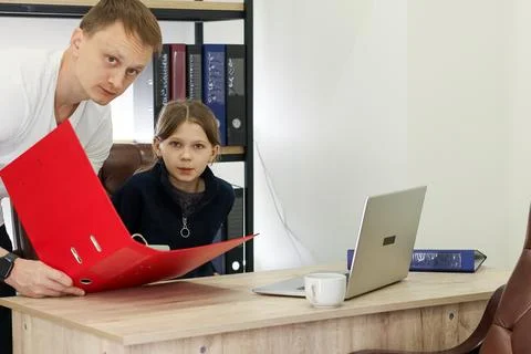 Man holding open red folder over desk toward girl Stock Photos