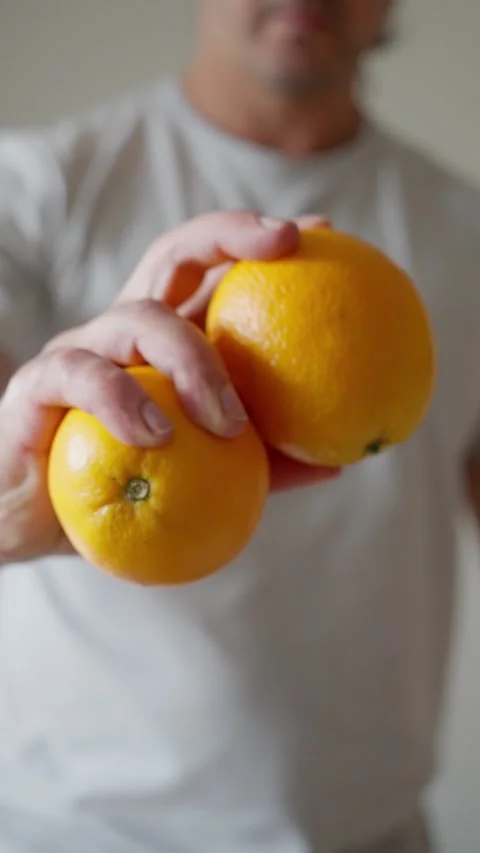 A man is holding oranges in his hands, showcasing their vibrant colors and Stock Footage 311052193