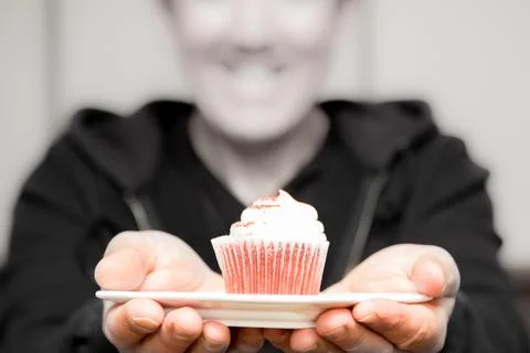 Man holding out a pink cupcake to his sweetheart Stock Photos