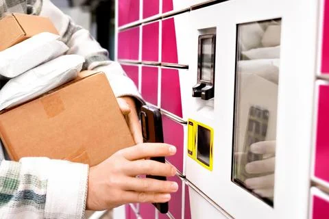 Man holding packages using a smartphone at a contactless parcel locker term.. Stock Photos