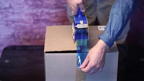 Man holding packing machine and sealing cardboard box with duct tape Stock Footage 148867021